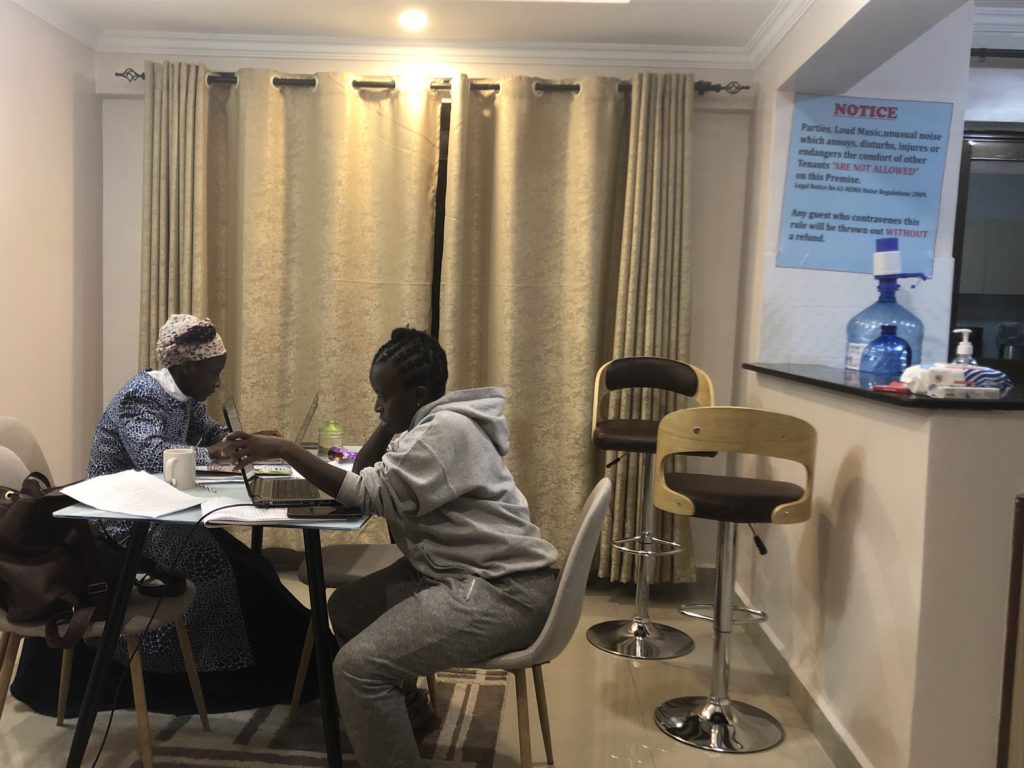 Qhala researchers in a Nakuru Airbnb, where they stayed when conducting field interviews. The Airbnb's rules are posted on the wall. Photo credit: T. Waithira, Qhala researcher