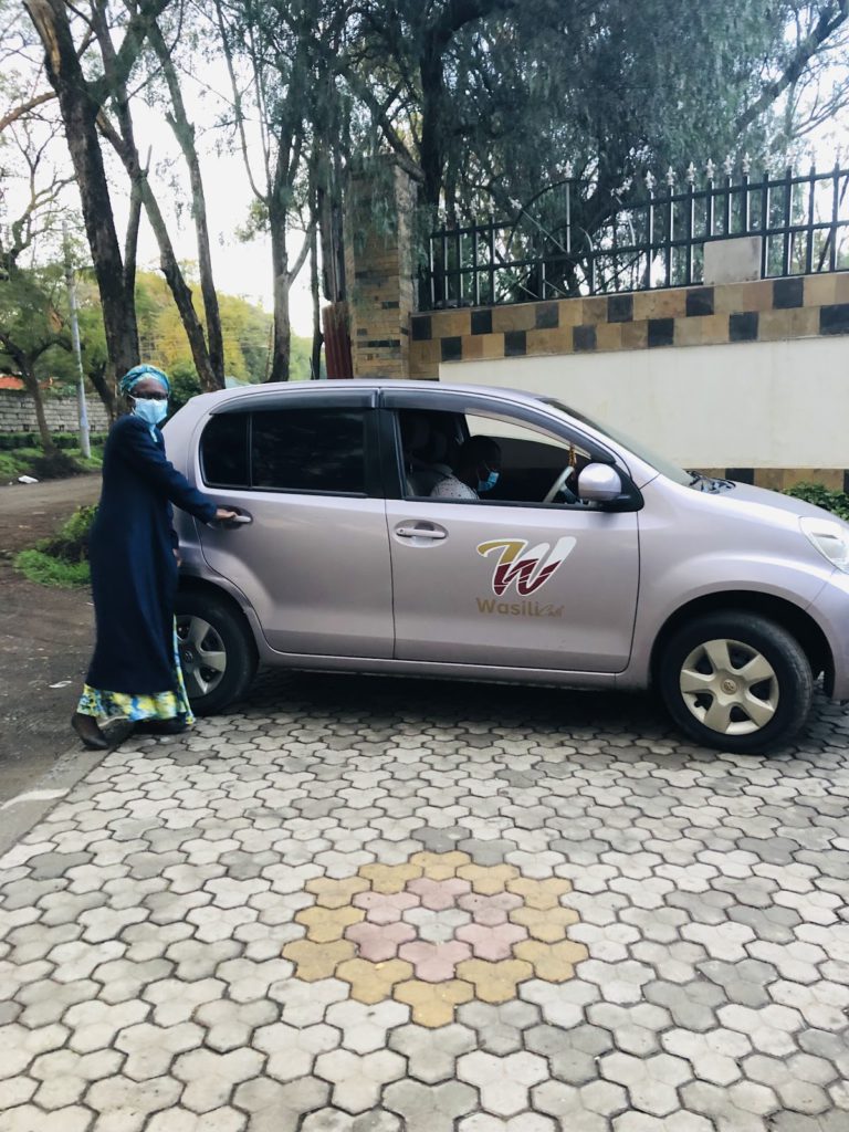 A car with the wasili logo and a lady opening the door to board